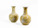 une paire de vases jaunes ornés de fleurs blanches sur fond blanc