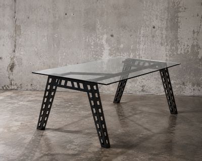 une photo d'une table en verre et en métal dans une pièce en béton