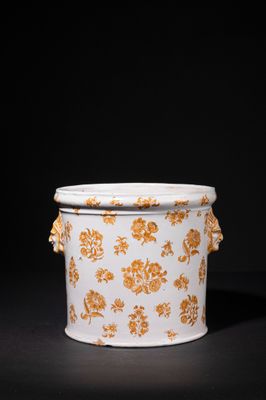 an orange and white vase with flowers on it on a black surface