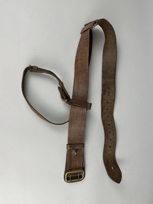 une vieille ceinture en cuir marron avec une boucle en métal sur un fond blanc