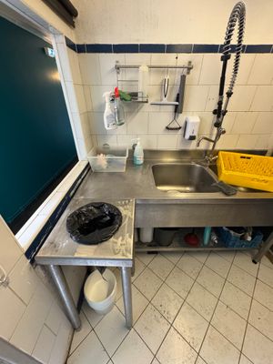 a kitchen with a sink, stove, and trash can