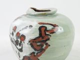 a small vase with a painting on it sitting on a table