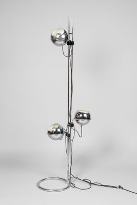 un lampadaire chromé muni de trois boules chromées sur son socle