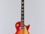 une guitare électrique rouge et jaune accrochée à un mur blanc