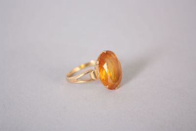 un gros plan d'une bague ornée d'une pierre orange sur un fond blanc
