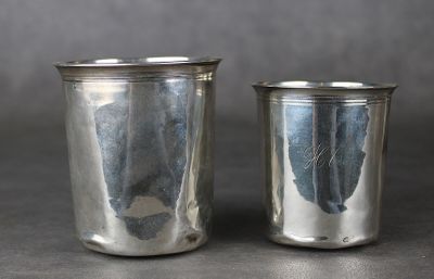 une paire de verres à shot en métal argenté posés sur une table avec un fond gris
