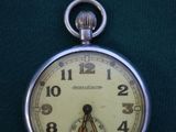 a close up of a pocket watch on a green surface