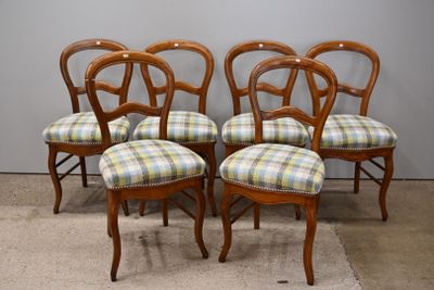 quatre chaises en bois aux assises recouvertes d'un tissu à carreaux, devant un mur gris