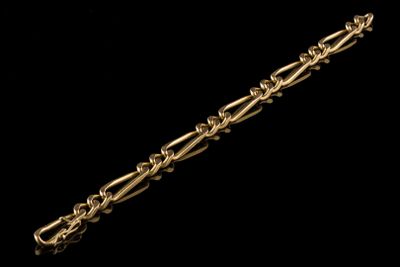 gros plan d'un bracelet en chaîne en or sur fond noir