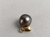 a close up of a black pearl with a gold clasp on a white surface