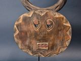 a wooden mask with horns on a stand on a blue background