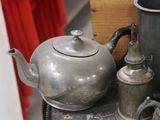 a silver tea pot sitting on top of a table next to a cup