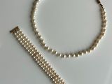 a close up of a white pearl bracelet with a gold clasp