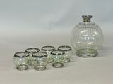 six glasses and a decanter sitting on a table