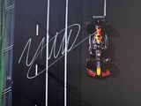 Une voiture de course Red Bull sur la piste, devant un grand écran