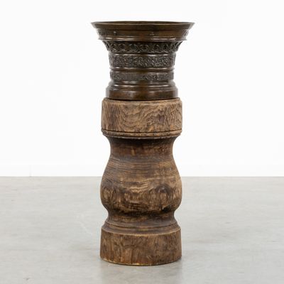 a wooden vase that is sitting on a cement floor