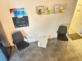 deux chaises dans un coin d'une pièce où sont accrochés des tableaux au mur