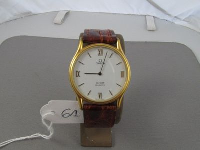 une montre-bracelet en or avec un cadran blanc posée sur une table