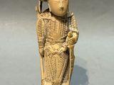 une figurine ancienne en ivoire sculpté représentant une femme avec un chapeau et une canne