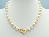 a white pearl necklace with a gold clasp on a mannequin