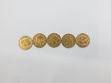 a group of five gold coins sitting on top of a white surface