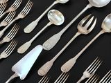 many spoons and forks laid out on a table