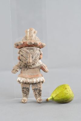 une figurine représentant un homme debout à côté d'une poire