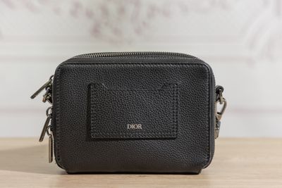 a black leather camera bag sitting on top of a wooden table