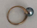 une image représentant une bague ornée d'une perle noire sur un fond blanc