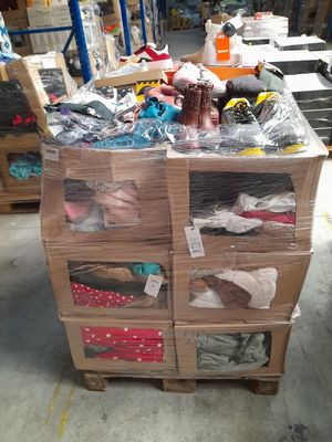 Des cartons contenant des articles divers sont empilés sur une palette dans un entrepôt