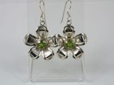 sterling silver flower earrings with peridot stones on a clear acrylic stand