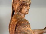 wooden statue of a woman holding a cane and a hat