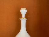 un vase blanc posé sur un comptoir, avec une horloge accrochée au mur derrière lui