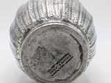 an old silver vase sitting on top of a white surface