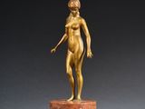 a gold statue of a woman standing on top of a marble base