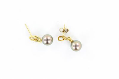 une paire de boucles d'oreilles en perles et or sur fond blanc