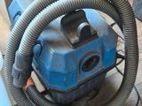 a blue vacuum cleaner sitting on the floor next to a bucket