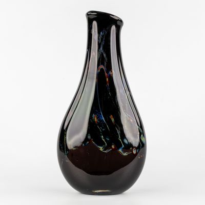 un vase noir posé sur une surface blanche