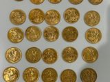 a close up of a pile of gold coins on a white surface