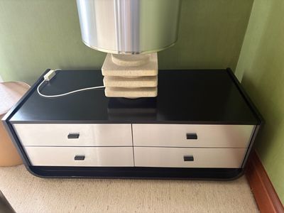 a black and white dresser with a lamp on top of it