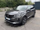 La voiture grise est garée sur un parking près d'une clôture.