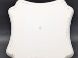 an old white plate with a metal stand on a gray background