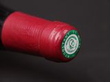 a close up of a red wine bottle with a green cap
