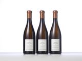three bottles of wine are lined up on a table