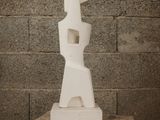 a white sculpture sitting on top of a wooden stool