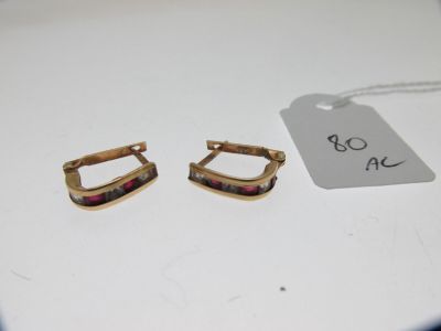 Deux paires de boucles d'oreilles sont posées sur une table, accompagnées d'une étiquette de prix