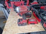 a red cordless drill and two other tools on a table