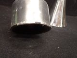 two silver vases sitting on a black surface