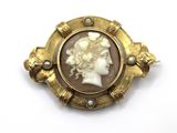 a close up of a gold broochle with a woman ' s face