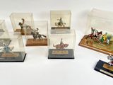 several miniature figurines of people riding horses and horses in glass cases